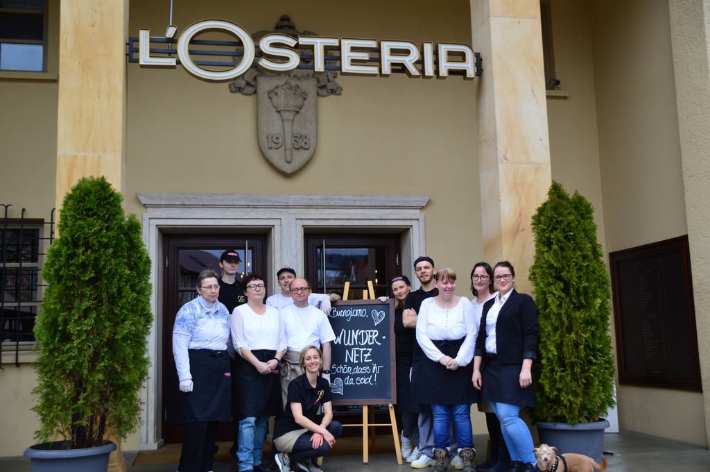 Gruppenfoto mit unseren Wundernetz-Kollegen und dem netten Team der L'Osteria vor dem Eingang des Restaurants in Amberg.